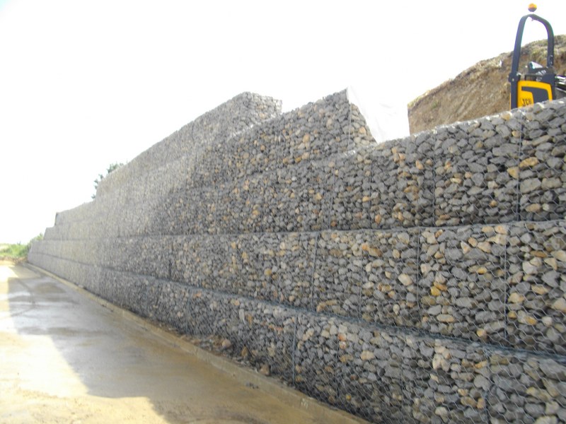 Muro feito de pedras redondas, preso com rede de arame de aço (gabião de  pedra de ferro)